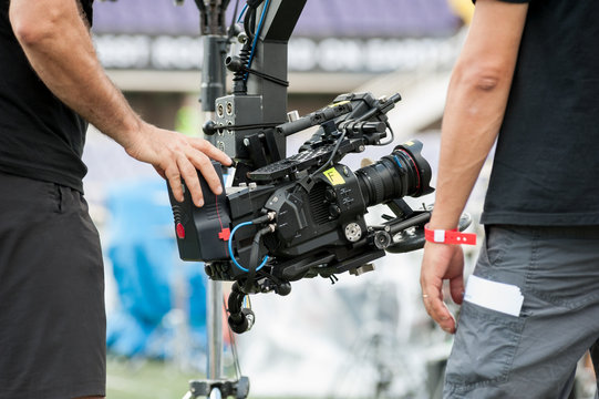 Technical camera operators set professional video camera on a large crane jib arm.

