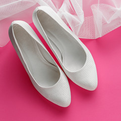 White wedding shoes on pink background