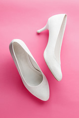 White wedding shoes on pink background