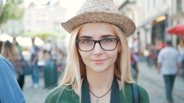 portrait of a happy beautiful blond girl with glasses, a hat and a blue jeans jacket