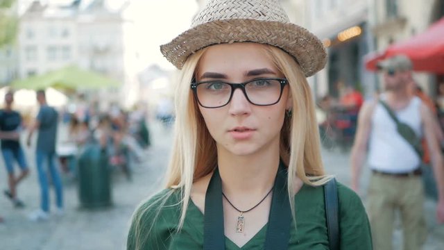 portrait of a beautiful blond girl with glasses, a hat and a blue jeans jacket.