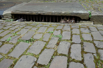old sewer at the border of a street with moss