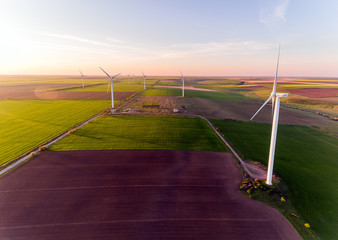 Obraz premium Aerial view looking across wind turbines in motion on a summers day