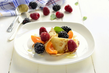 Сrepes, fresh berries and honey on wooden background