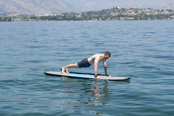 Man doing push-ups while floating on paddle board in summer.