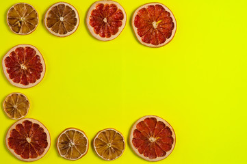 Scattered dried slices grapefruit and lemon on yellow background. Top view with copy space