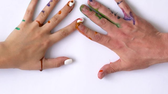 Creative concept - man and woman make prints of their painted hands on a white background