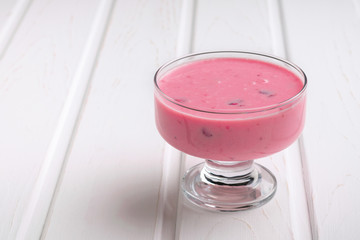 Yogurt is pink in a glass cup with fresh strawberry. Place for text