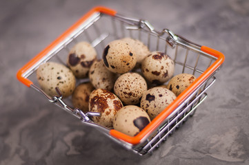 Full metal glossy market basket of spotted fresh quail eggs on old broken worn gray cement floor