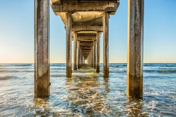 Keuken foto achterwand Badkamer Symmetrisch schot onder Scripps Pier met palen, pilaren, zonnig zonlicht, zon, blauwe lucht, golven tijdens gouden zonsondergang in La Jolla, San Diego, Californië