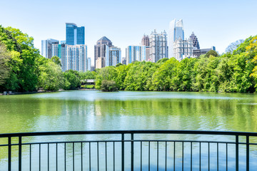 Cityscape, skyline view in Piedmont Park in Atlanta, Georgia green foliage, trees, scenic water, urban city skyscrapers downtown at Lake Clara Meer by railing