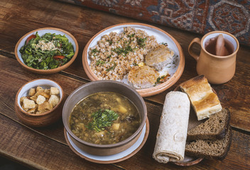 Middle Eastern cuisine dishes in ceramic plates on a wooden table. Lentil soup, salad with lettuce...
