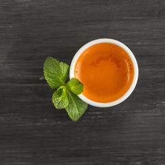Top view of carrot juice and mint leaves on wooden table.