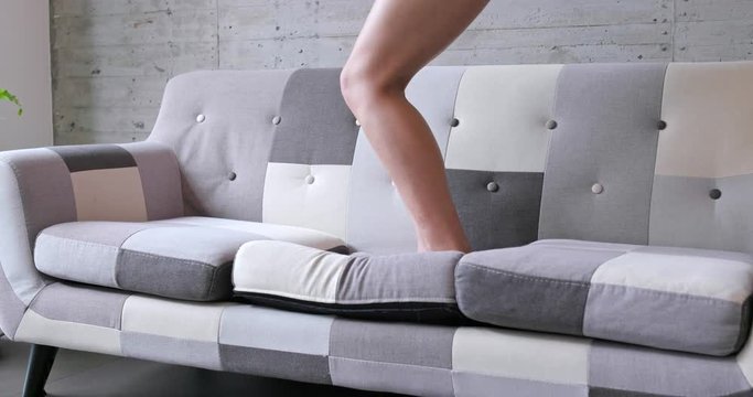 Excited woman dancing on sofa