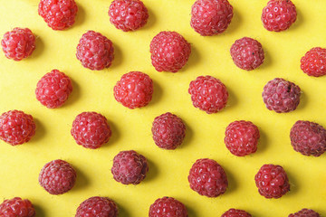 Juicy red raspberries on yellow background. Beautiful abstract texture for design. Top view