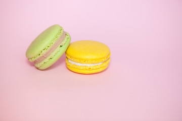 Green mint and yellow lemon macaroon on pink background