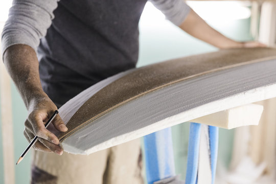 Male surfboard shaper working on foam - Powered by Adobe