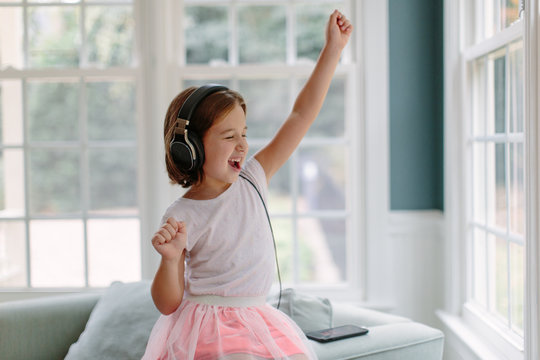 Cute young girl listening to music wearing headphones
