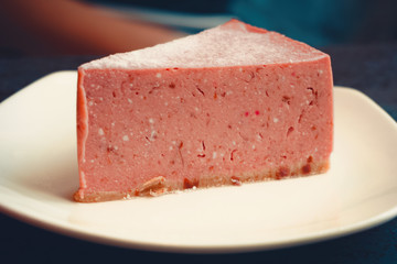 Close-up of a stone table with a cup of coffee and a delicious piece of cake. Pink piece of cheesecake. Fashionable new interior. Perfect background for websites or coffee shops