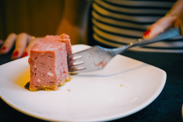 Close-up of a stone table with a cup of coffee and a delicious piece of cake. Model holds the mug and enjoys. Fashionable new interior. Perfect background for websites or coffee shops