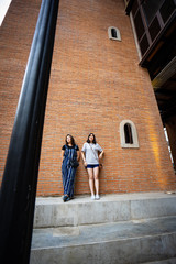 Beautiful modern girls near the orange brick wall. Youth hipster style.