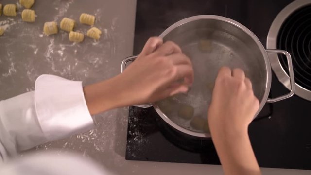 4K detail from above putting gnocchi in boiling water in kitchen
