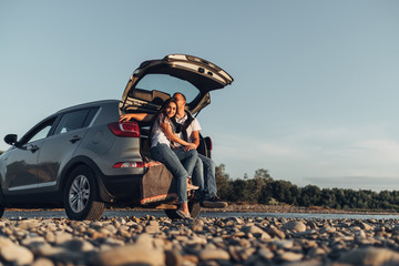 Happy Couple on Roadtrip into the Sunset in SUV Car