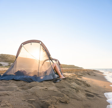 Woman sleeping in translucent tent on the beach