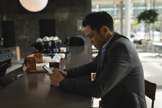 Businessman using his phone at the cafeteria counter