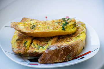 Fried bread in an egg with dill. Fried bread on a plate. Breakfast - bread and eggs.