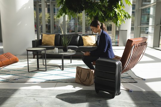 Businesswoman using smartphone while sitting in lobby