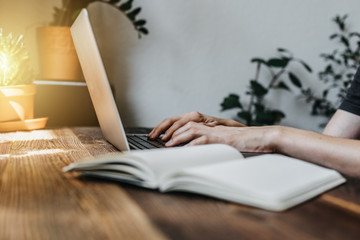 Student sitzt am Laptop und schreibt ein Buch liegt im Vordergrund 