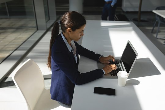 Side view of businesswoman working on laptop in office