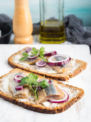 Danish open sandwich smorrebrod with salted herrings, red onion, butter. Traditional snack