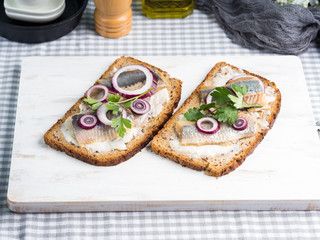 Danish open sandwich smorrebrod with salted herrings, red onion, butter. Traditional snack