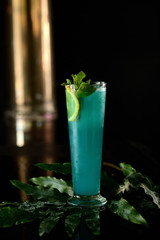 green cocktail with mint, lemon and ice on a dark background