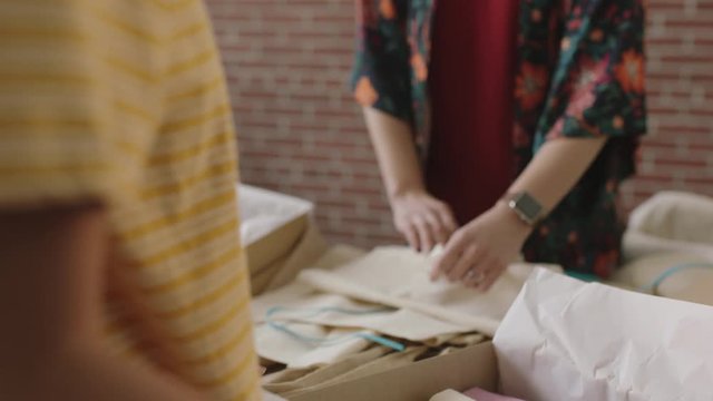 slow motion young entrepreneur women in successful startup business working packaging fashion handbags in parcel box workspace studio 