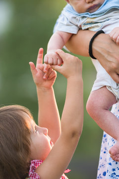 Sister holding gently her newborn borther's tiny hand