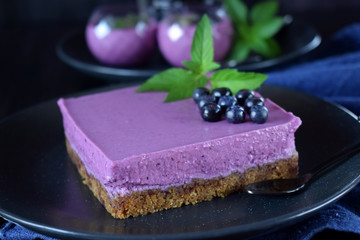 Square mousse cake with bilberries against the dark background