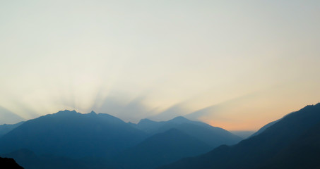 sun rises behind a mountain