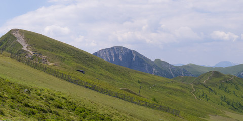 Obraz premium hiking path on sloped hills with a view on mountain ridges on cloudy day