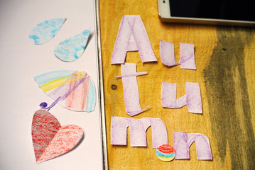 inscription "autumn", letters and figures cut from paper on a wooden background