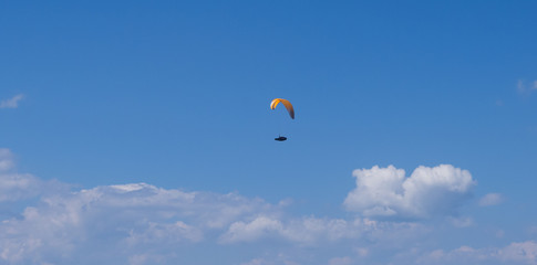 paragliding above clouds in alpine mountains with blue sky