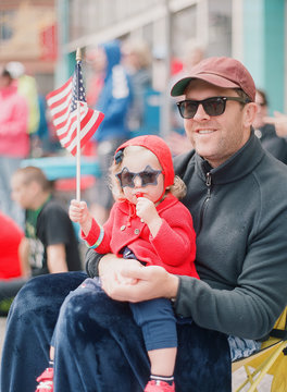dad holding baby girl at fourth of july parade