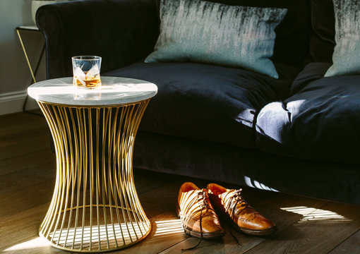 The End Of The Week. A Glass Of Whisky, A Neck Tie And Brown Brogue Shoes In A Modern Room Setting. Dramatic Lighting.