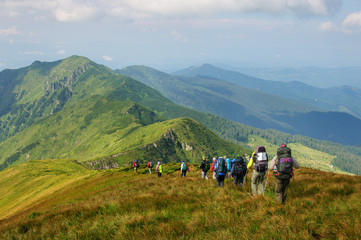 Group of tourists with large backpacks are on mountain