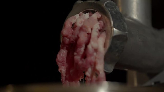 Close up shot of a food grinder grinding raw meat in the kitchen. Production of minced meat from pork meat.