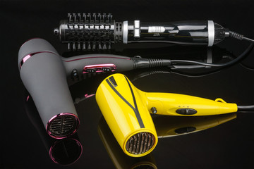 Three hair dryers on the black mirror background