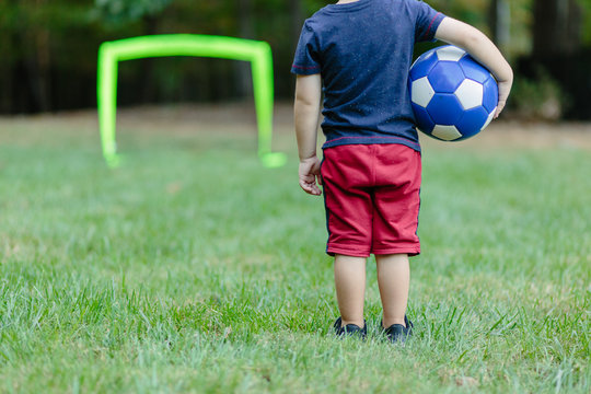 Fototapeta Young boy looking towards a practice goal with a soccer ball under his arm