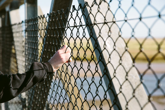 Hand holding onto a wire fence